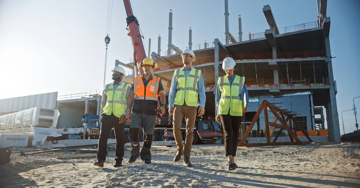 Four constructions workers walking through a construction site. | Patrick Daniel Law