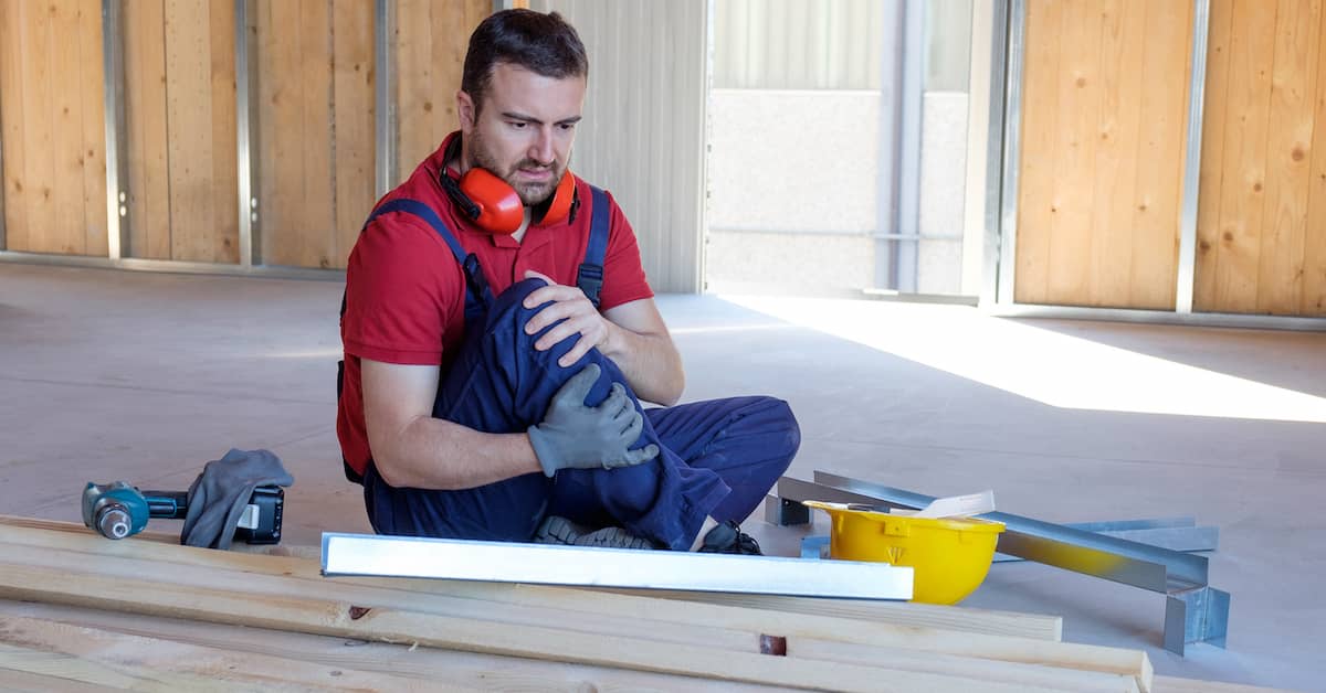 construction worker holding his knee after a work-related injury