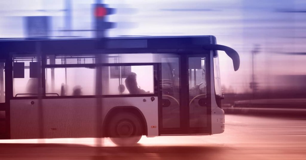 bus traveling through intersection on a city road in the early morning