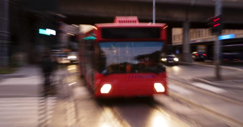 city bus driving down a city street at dusk