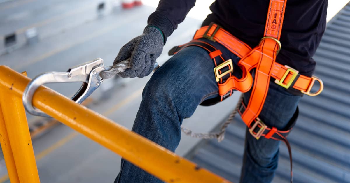 construction worker hooking onto guardrail to prevent fall from heights