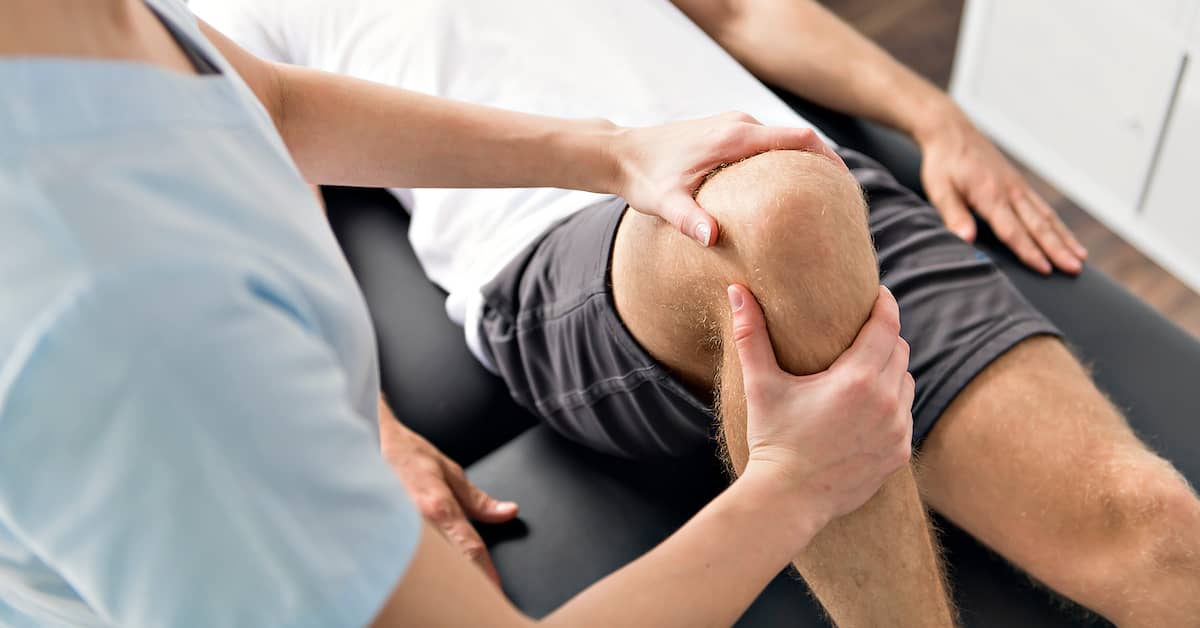 Physical therapist performing knee exercises with patient.