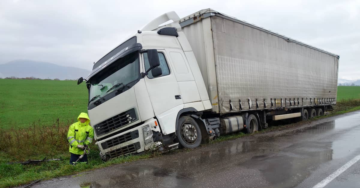 insurance adjuster inspecting wrecked 18-wheeler on the side of a road