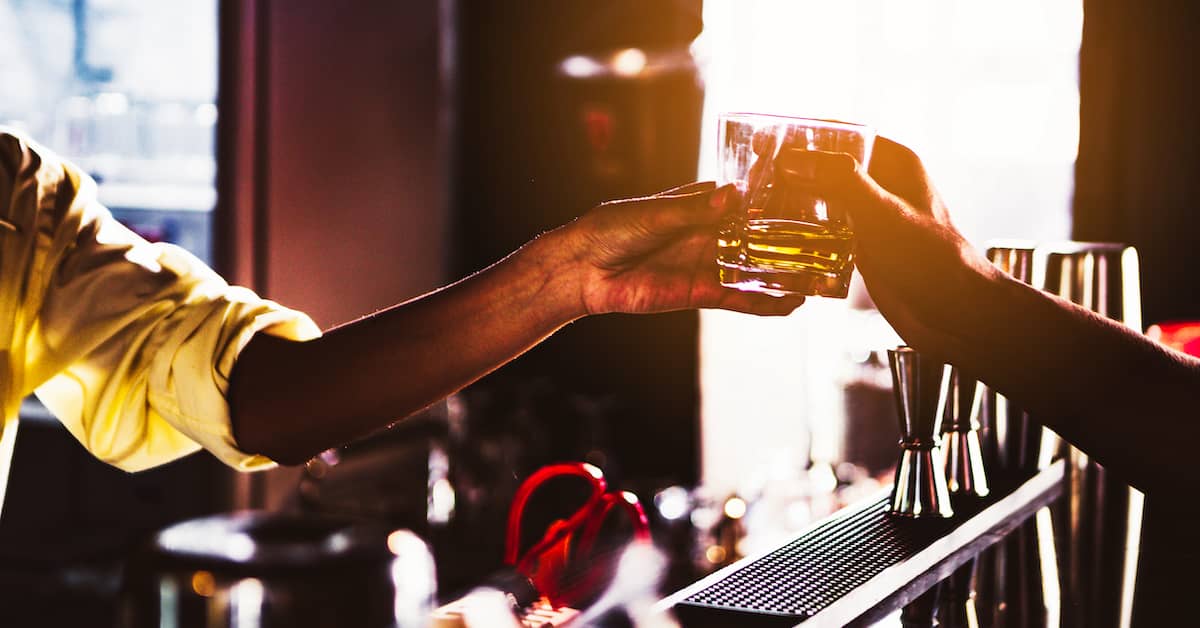 Bartender hands patron a drink. | Patrick Daniel Law