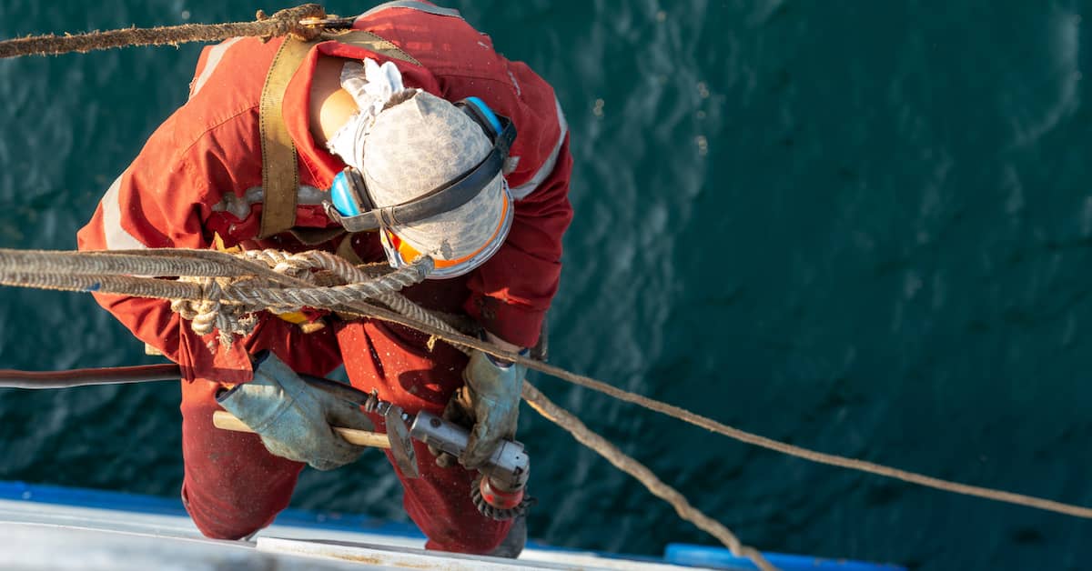 Maritime worker hangs off side of ship. | Patrick Daniel Law